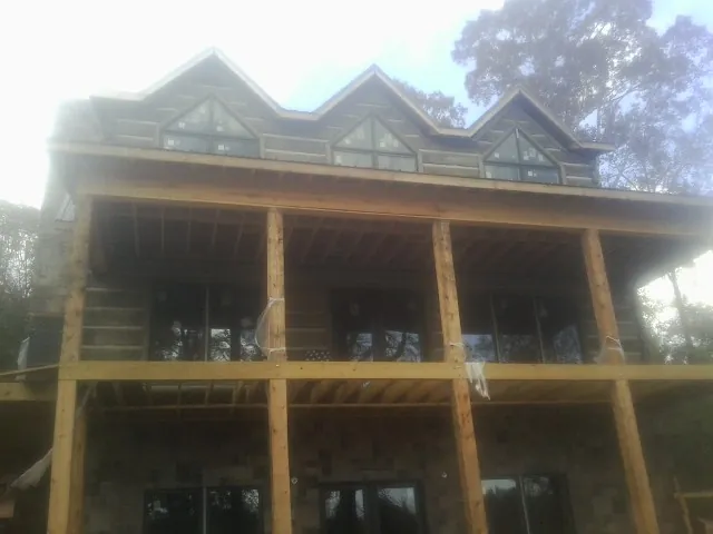 Dormers and porch framing on a large log home under construction — Roof Coating work by our crew in North East